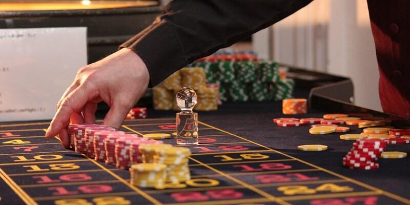 roupier della roulette che posiziona diversi fiches su una fila di numeri del tavolo ad gioco