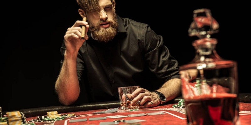 Ragazzo con la barba e un sigaro in mano che gioca al poker