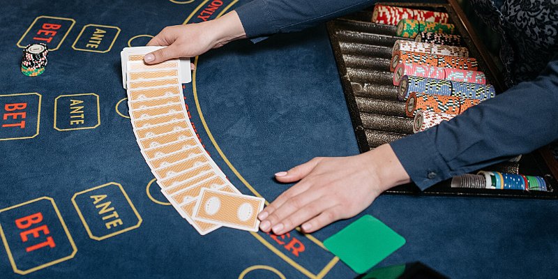 Croupier che estende le carte sul tavolo del Baccarat – Come si gioca a Baccarat